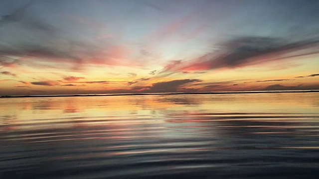 海滩上的日落-宁静的田园诗般的景象，一个金色的日落在海上，海浪慢慢溅在沙滩上视频素材