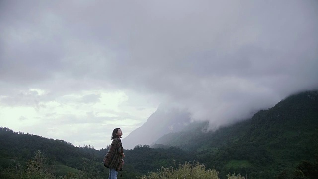 年轻女子和徒步旅行者张开双臂站在山顶视频素材