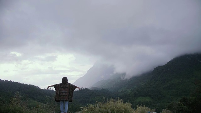 年轻女子和徒步旅行者张开双臂站在山顶视频素材