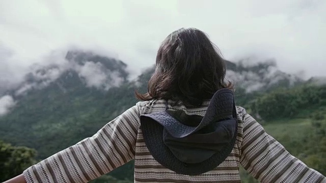 女游客探索山坡，站在山顶，欣赏周围的壮丽的山在一个美丽的阳光灿烂的日子视频素材