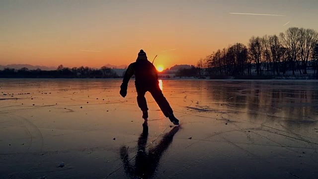 曲棍球运动员在结冰的湖面上滑向夕阳视频素材