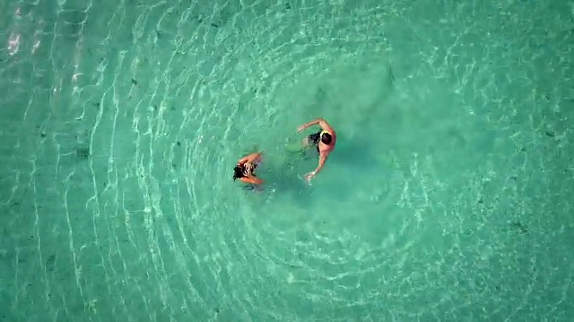 鸟瞰男人和女人在绿松石海中玩耍。视频素材