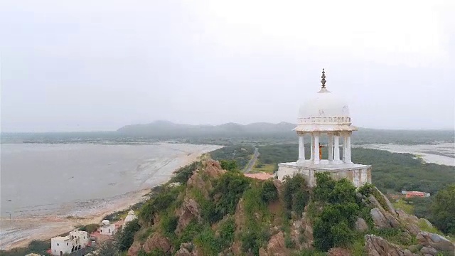 一架移动的无人机拍摄了一名印度古典舞蹈演员在位于沙漠山顶的大理石圆顶建筑上跳舞的画面。视频素材