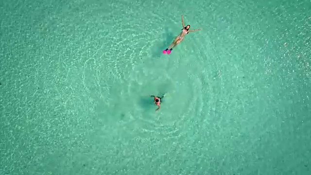 鸟瞰图的男人和女人戴着面具和鳍状肢在他们的背部游泳。视频素材