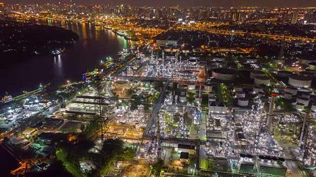 无人机在夜间以城市和河流为背景飞越炼油厂上空。由4K高清无人机拍摄。视频素材