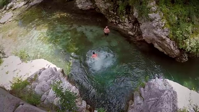 人们从岩石上跳到河里。视频素材