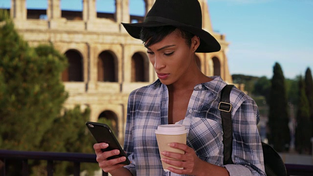 罗马非裔美国女性在罗马斗牛场(Colosseum)附近边喝咖啡边打电话视频素材