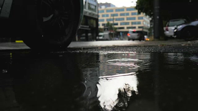 雨滴落在水坑和城市街道交通视频素材