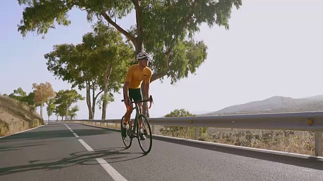 一名男子骑着一辆运动公路自行车在位于高山上的道路上骑行。视频素材