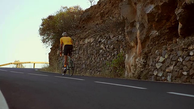 一名男子骑着一辆运动公路自行车在位于高山上的道路上骑行。在缓慢的运动。视频素材