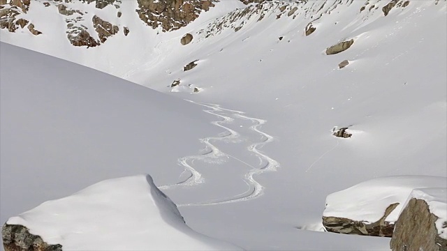 一名男子在山上滑雪，在粉状积雪上留下新的足迹。——慢动作视频素材