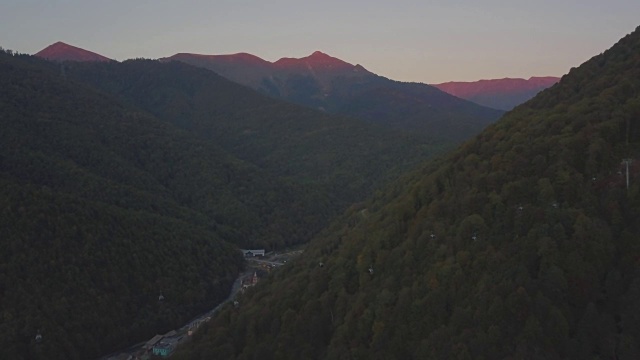 傍晚飞行穿过高山森林峡谷的索道进入夕阳视频素材