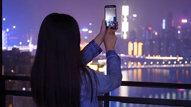 年轻女子正在拍摄城市夜景视频素材