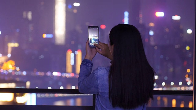 年轻女子正在拍摄城市夜景视频素材