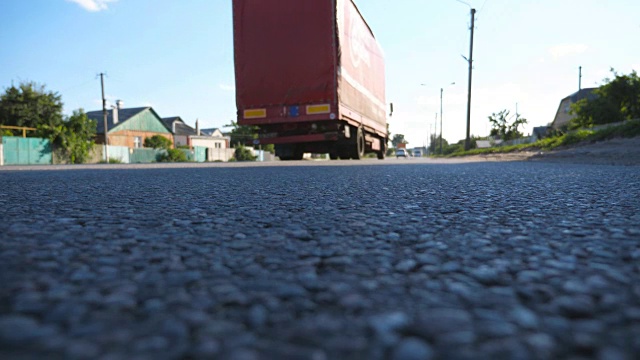 红色卡车在柏油路上行驶。在阳光明媚的夏日，汽车在高速公路上行驶。交通关闭。低角度视角慢动作视频素材