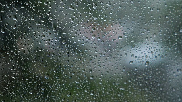 透过被雨覆盖的汽车挡风玻璃作为背景，模糊的交通视野。视频素材