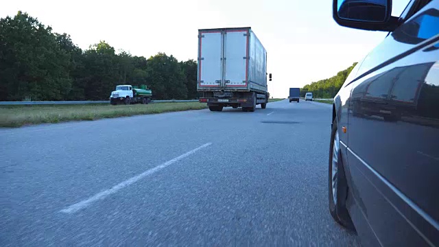 一辆黑色汽车在乡间的路上行驶。美丽的风景映照在车门上。农村地区的交通。观点慢动作视频素材