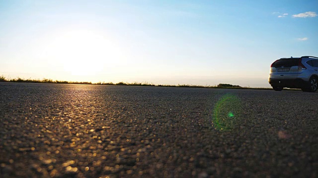 汽车在乡间的柏油路上行驶。汽车沿着公路行驶，背景是美丽的风景。乡间小路的景色。旅行的概念。慢动作视频素材