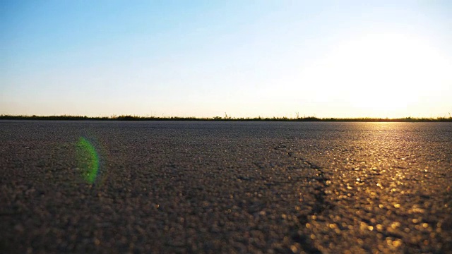 汽车在乡间的柏油路上行驶。汽车沿着公路行驶，背景是美丽的风景。乡间小路的景色。旅行的概念。慢动作视频素材