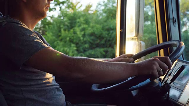 在阳光明媚的夏日，一个男人在乡村公路上驾驶着一辆卡车。白人司机在路上仔细观察。慢镜头视频素材