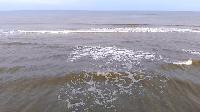 一浪一浪地涌向岸边，动作缓慢。海鸥飞过海浪视频素材