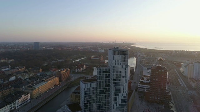 鸟瞰图Malmö城市天际线日落。无人机飞过城市和街道，从市中心的现代摩天大楼向后飞行视频下载