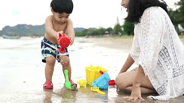 妈妈和儿子在沙滩上玩沙子玩具视频素材