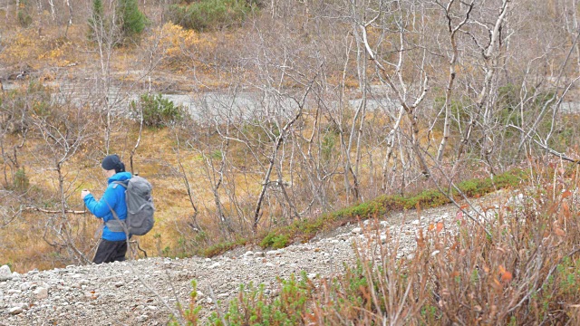 一个男人独自在一个美丽的公园里旅行。他下山去了。一个背包和一双北欧人专用的筷子。视频素材