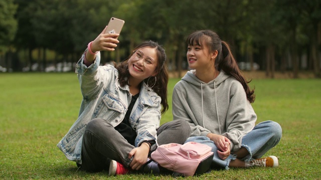 两个亚洲大学女孩使用手机在校园自拍视频素材