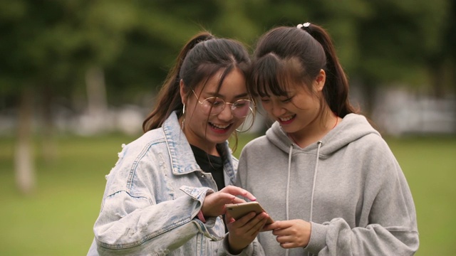 两个亚洲女大学生在校园里使用手机视频素材