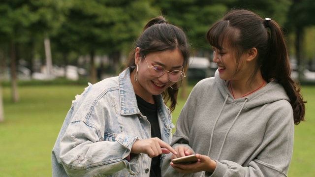 两个亚洲女大学生在校园里使用手机视频素材