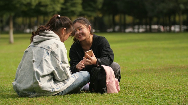 两个亚洲女大学生在校园里使用手机视频素材