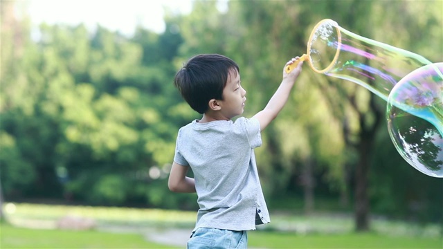 欢快的蹒跚学步的小男孩在公园里玩肥皂泡视频素材