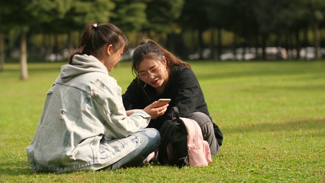 两个亚洲女大学生在校园里使用手机视频素材