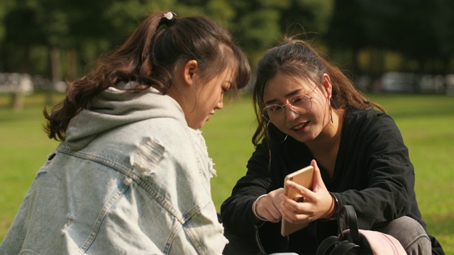 两个亚洲女大学生在校园里使用手机视频素材