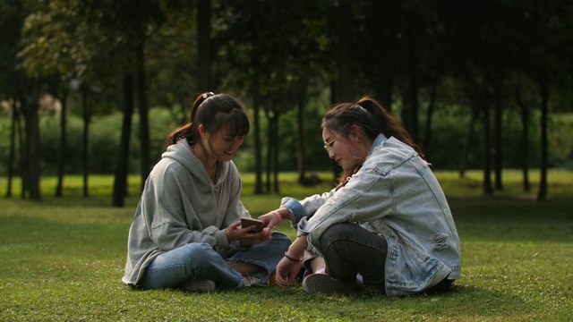 两个亚洲女大学生在校园里使用手机视频素材