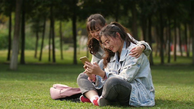 两个亚洲女大学生在校园里使用手机视频素材