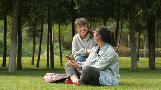 两个亚洲女大学生在校园里使用手机视频素材