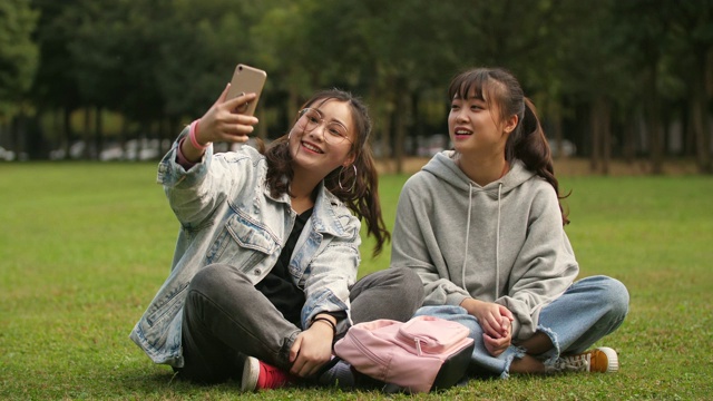 两个亚洲大学女孩使用手机在校园自拍视频素材