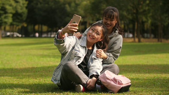 两个亚洲大学女孩使用手机在校园自拍视频素材