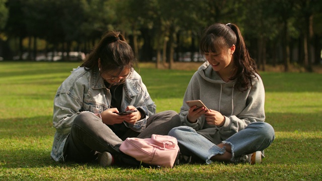 两个亚洲女大学生在校园里使用手机视频素材