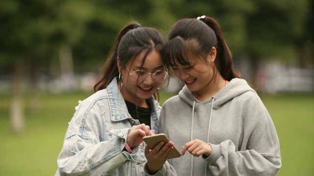 两个亚洲大学女孩在校园看手机视频素材