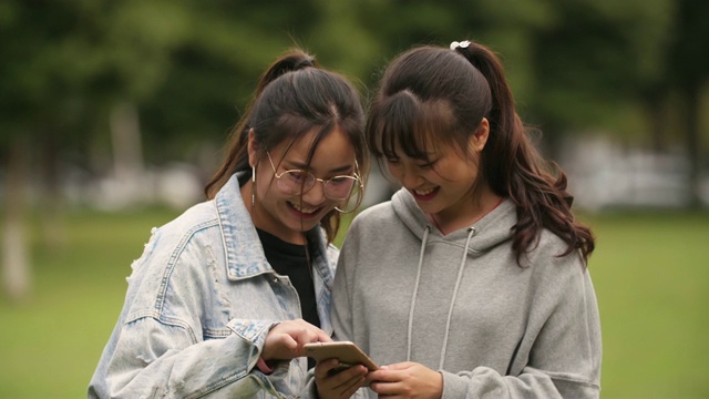 两个亚洲大学女孩在校园看手机视频素材