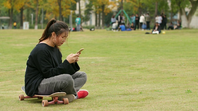 在校园草坪上使用手机的亚洲女大学生视频素材