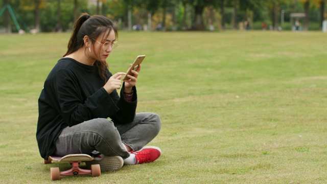 在校园草坪上使用手机的亚洲女大学生视频素材