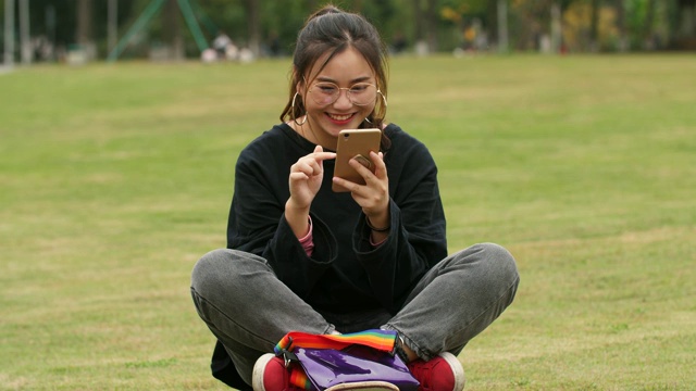 在校园草坪上使用手机的亚洲女大学生视频素材