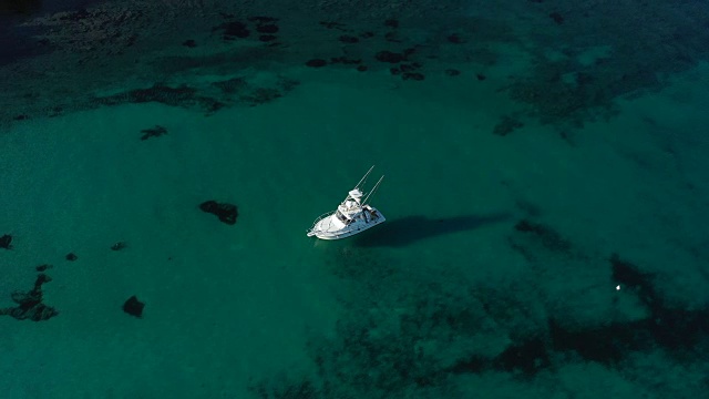 从上面的视频，鸟瞰一艘美丽的渔船在清澈透明的海面上。意大利撒丁岛。视频素材