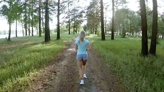 健康的年轻女子在城外慢跑。漂亮的运动女孩在森林小径上慢跑。视频素材