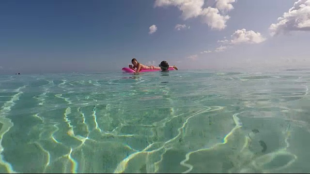 一个女人和一个小孩躺在海上的充气床垫上视频素材