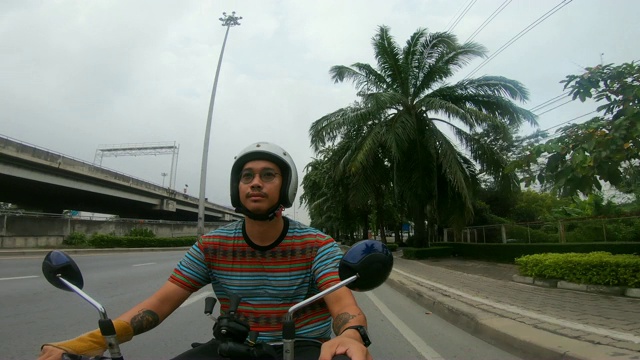 年轻的亚洲男子驾驶摩托车在曼谷的道路上。视频素材